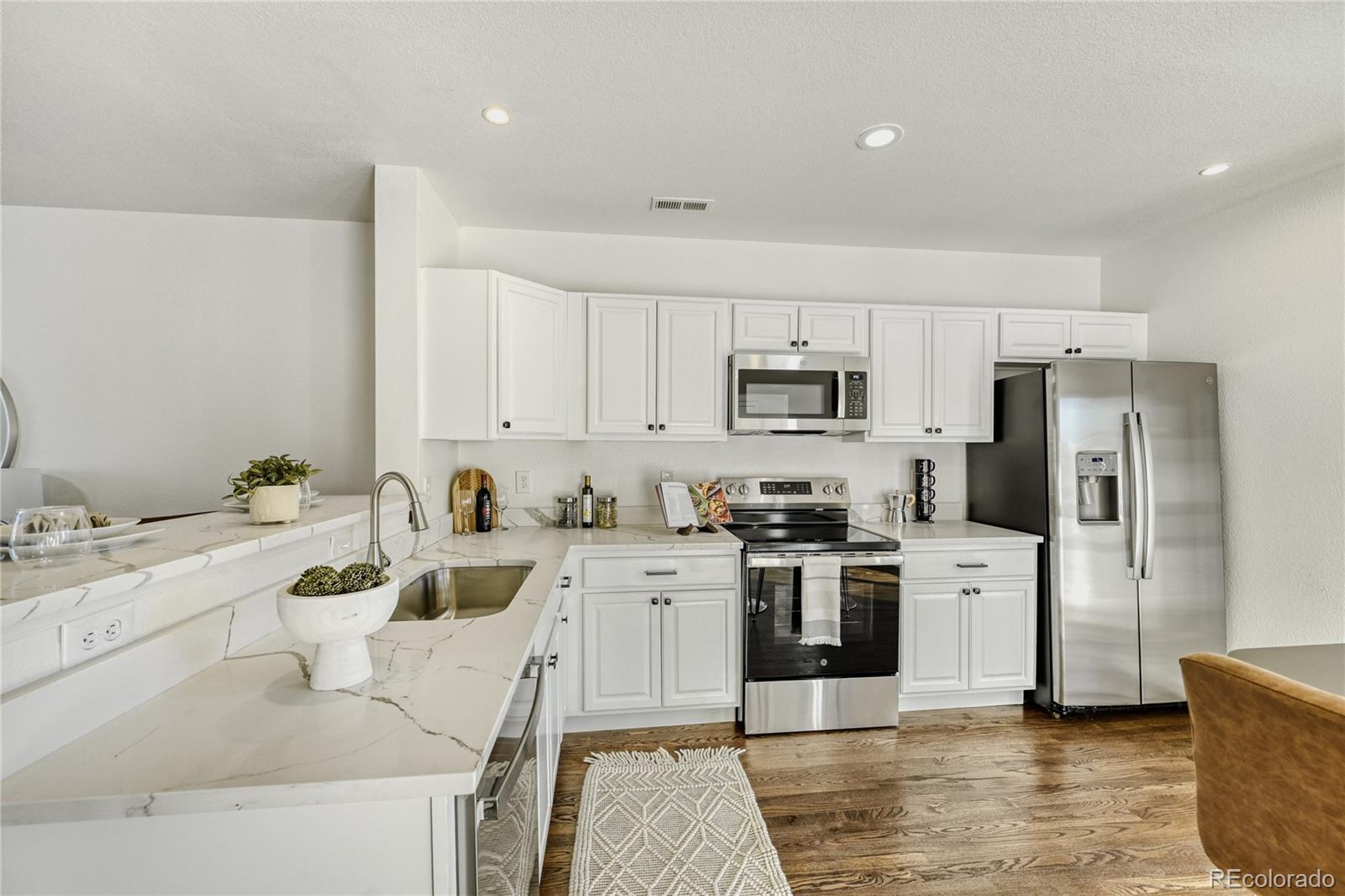 6130 Gorham Street Frederick, CO 80530 - Photo 10 of 47 a kitchen with stainless steel appliances kitchen island granite countertop a refrigerator sink and white cabinets