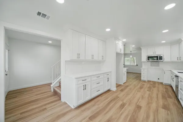 a large kitchen with wooden floor and stainless steel appliances
