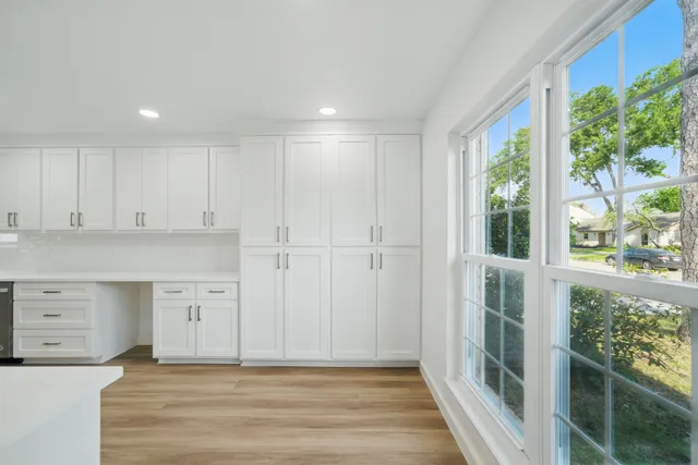 a view of a kitchen with white cabinets and wooden floor