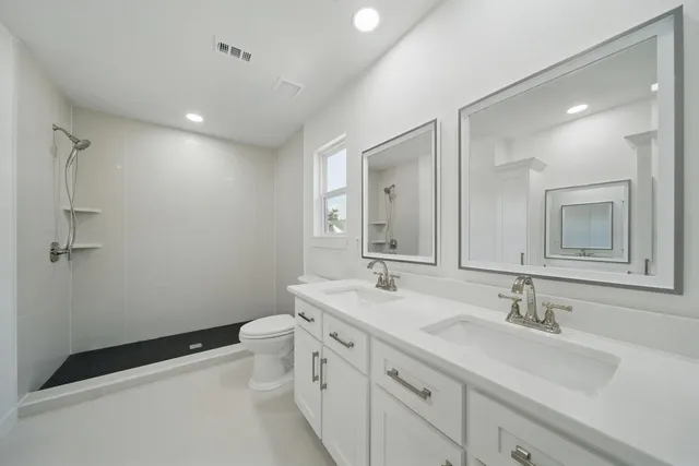 a bathroom with a double vanity sink toilet and mirror