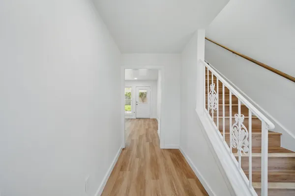 a view of a hallway with wooden floor and staircase