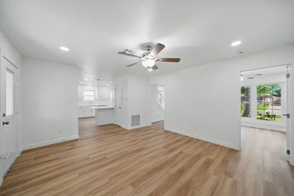 a view of an empty room with a window and wooden floor