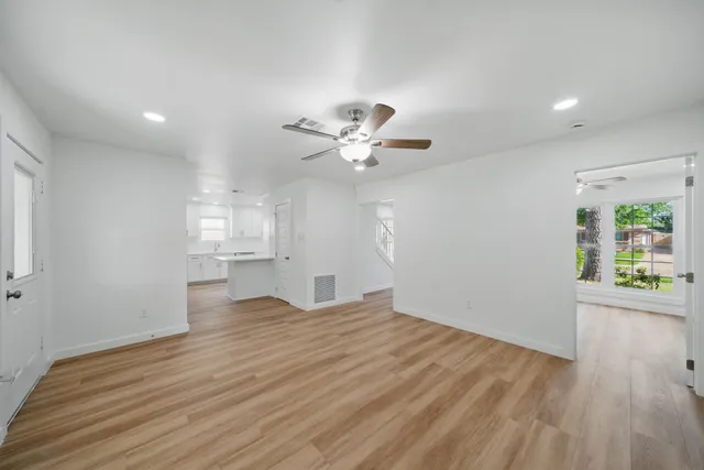 a view of an empty room with a window and wooden floor