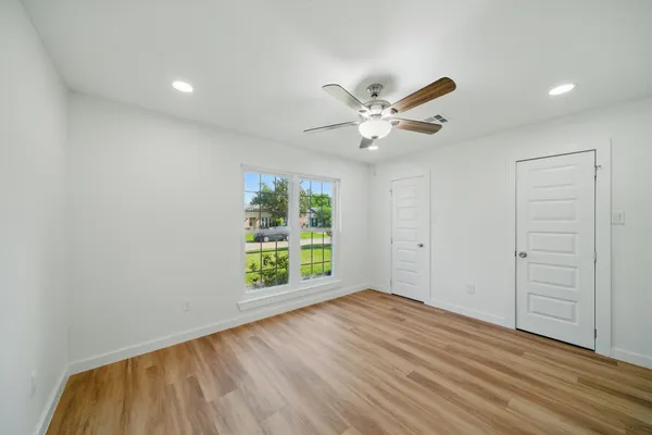 an empty room with wooden floor and windows