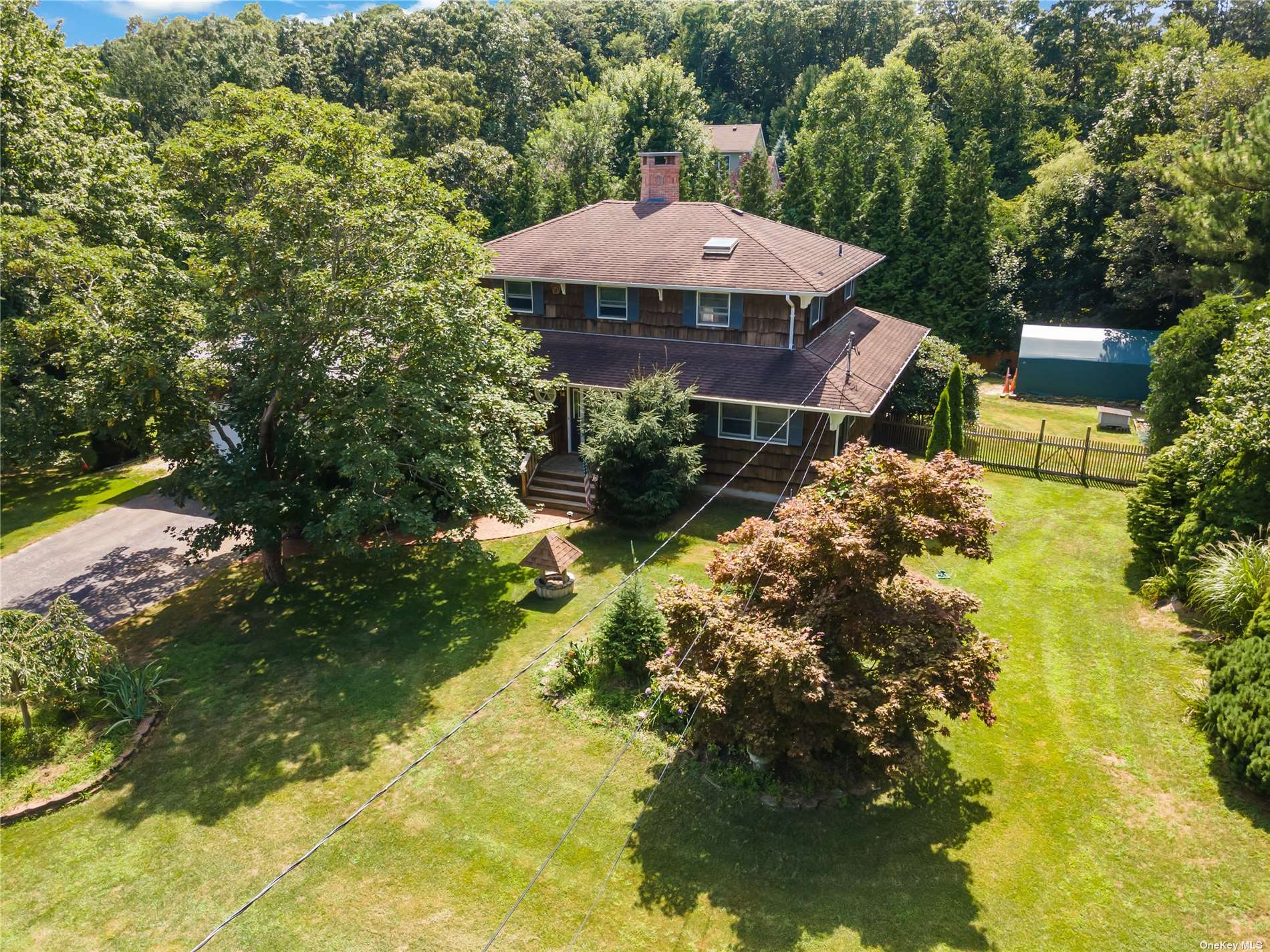 an aerial view of a house with garden space and trees all around