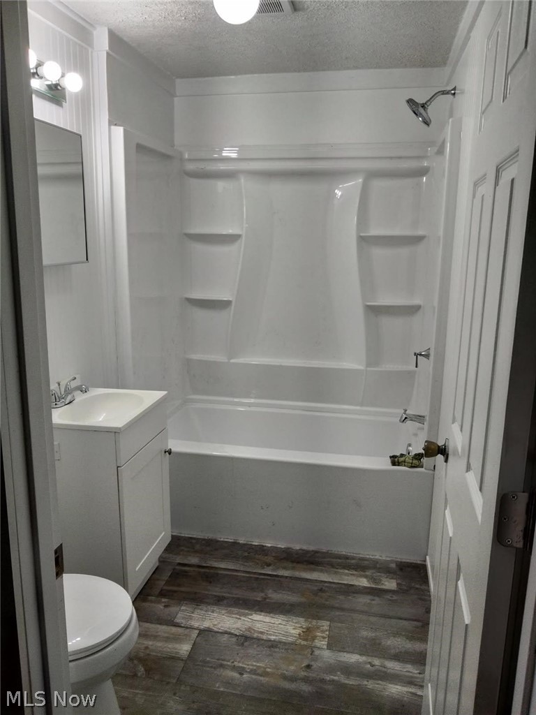 3995 Clay Pike Road Cambridge, OH 43725 - Photo 10 of 10 Bathroom with vanity, a textured ceiling, dark wood finished floors, and shower / washtub combination