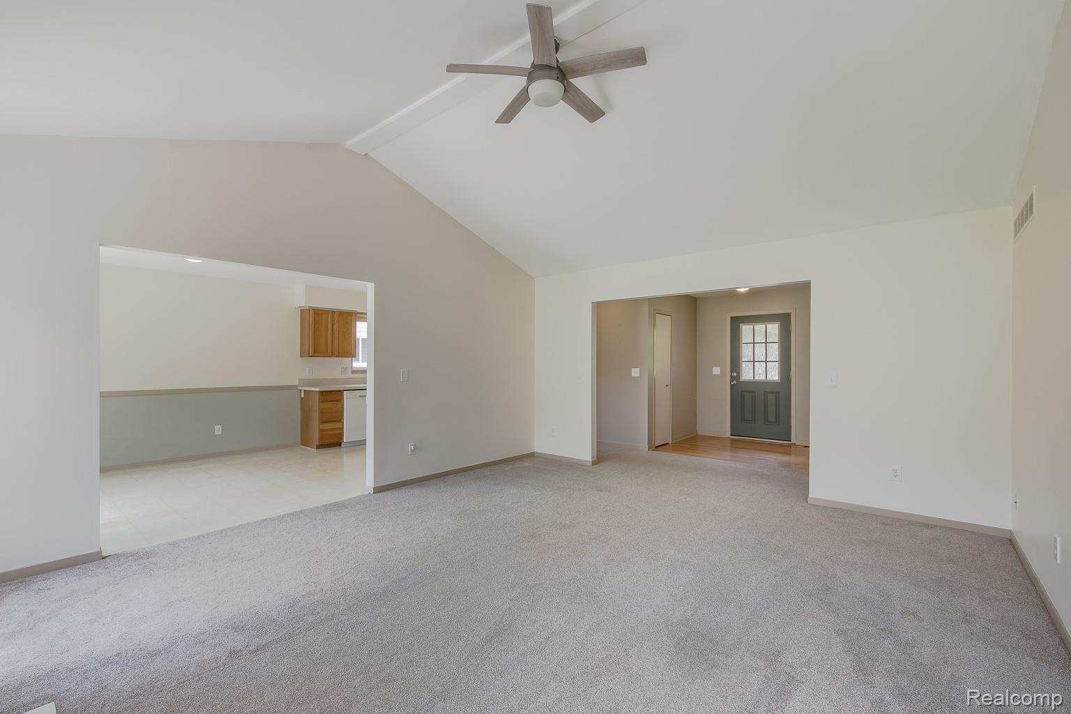 312 Reid Road Highland, MI 48357 - Photo 13 of 47 Spacious living area featuring vaulted ceilings, light gray carpeting, and a modern ceiling fan