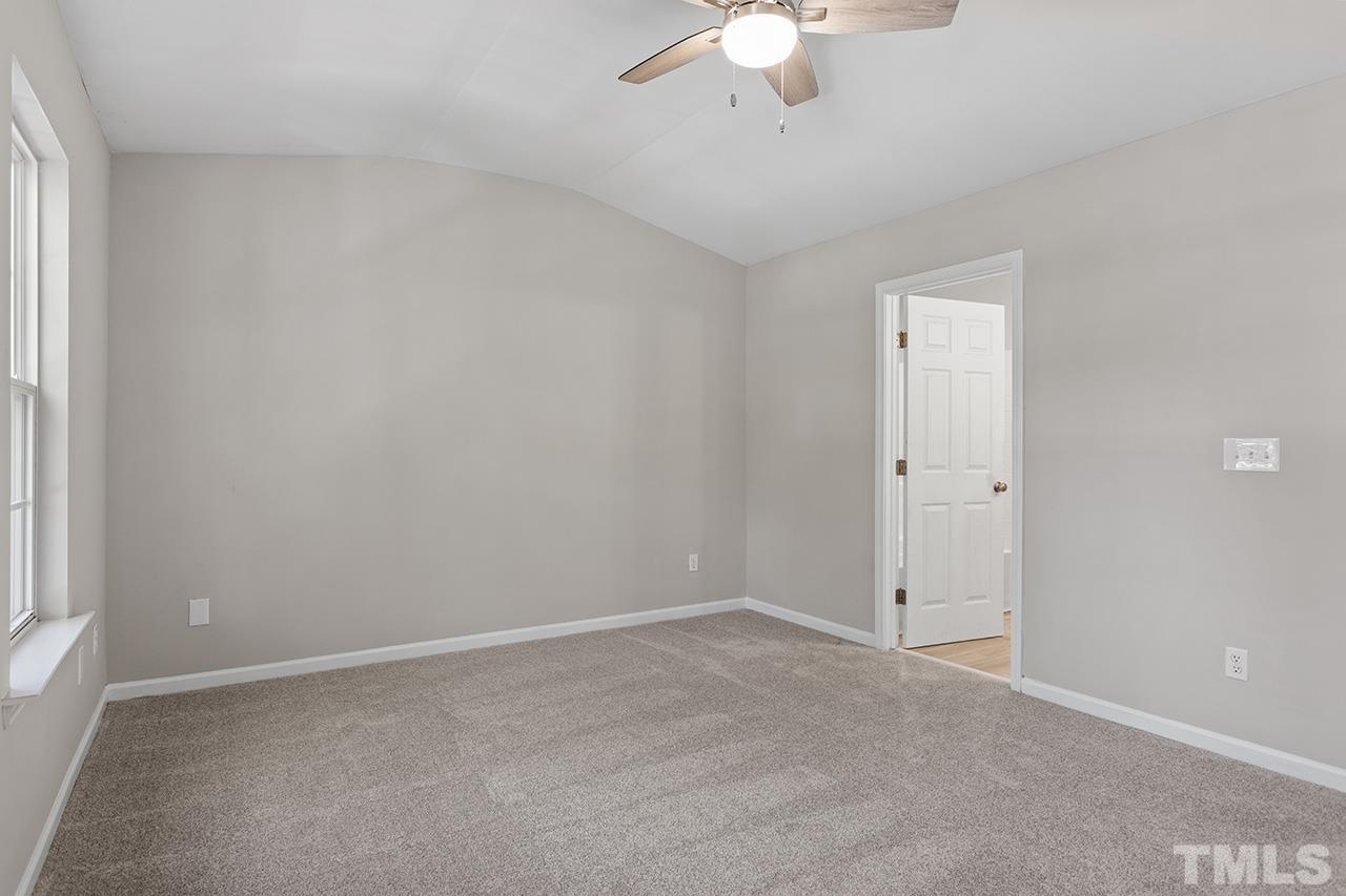 8516 Micollet Court Raleigh, NC 27613 - Photo 16 of 26 an empty room with a chandelier fan and windows