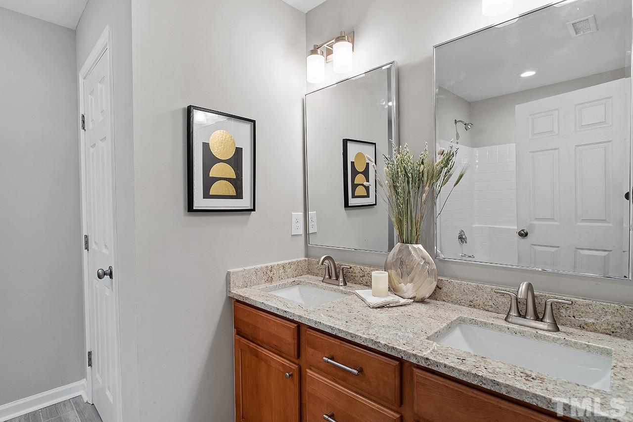 8516 Micollet Court Raleigh, NC 27613 - Photo 19 of 26 a bathroom with a granite countertop sink a mirror and a shower