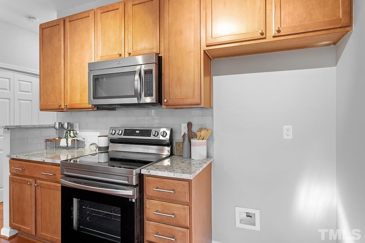 8516 Micollet Court Raleigh, NC 27613 - Photo 4 of 26 a kitchen with stainless steel appliances granite countertop white cabinets and a stove top oven