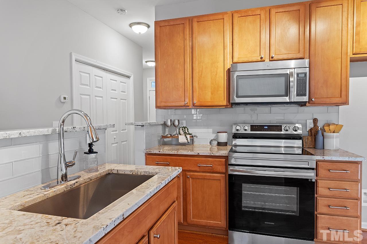 8516 Micollet Court Raleigh, NC 27613 - Photo 5 of 26 a kitchen with granite countertop a sink stainless steel appliances and cabinets