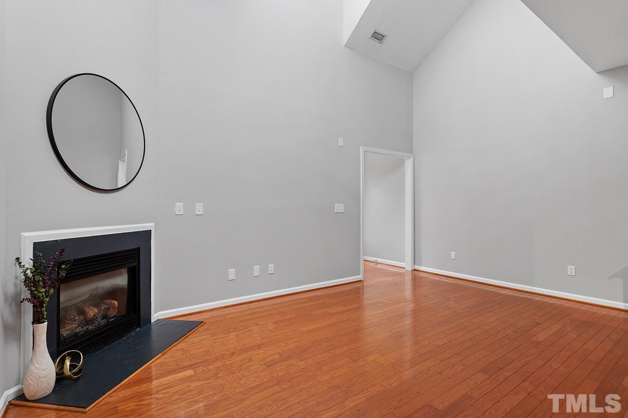 8516 Micollet Court Raleigh, NC 27613 - Photo 7 of 26 a view of an empty room with wooden floor and a fireplace