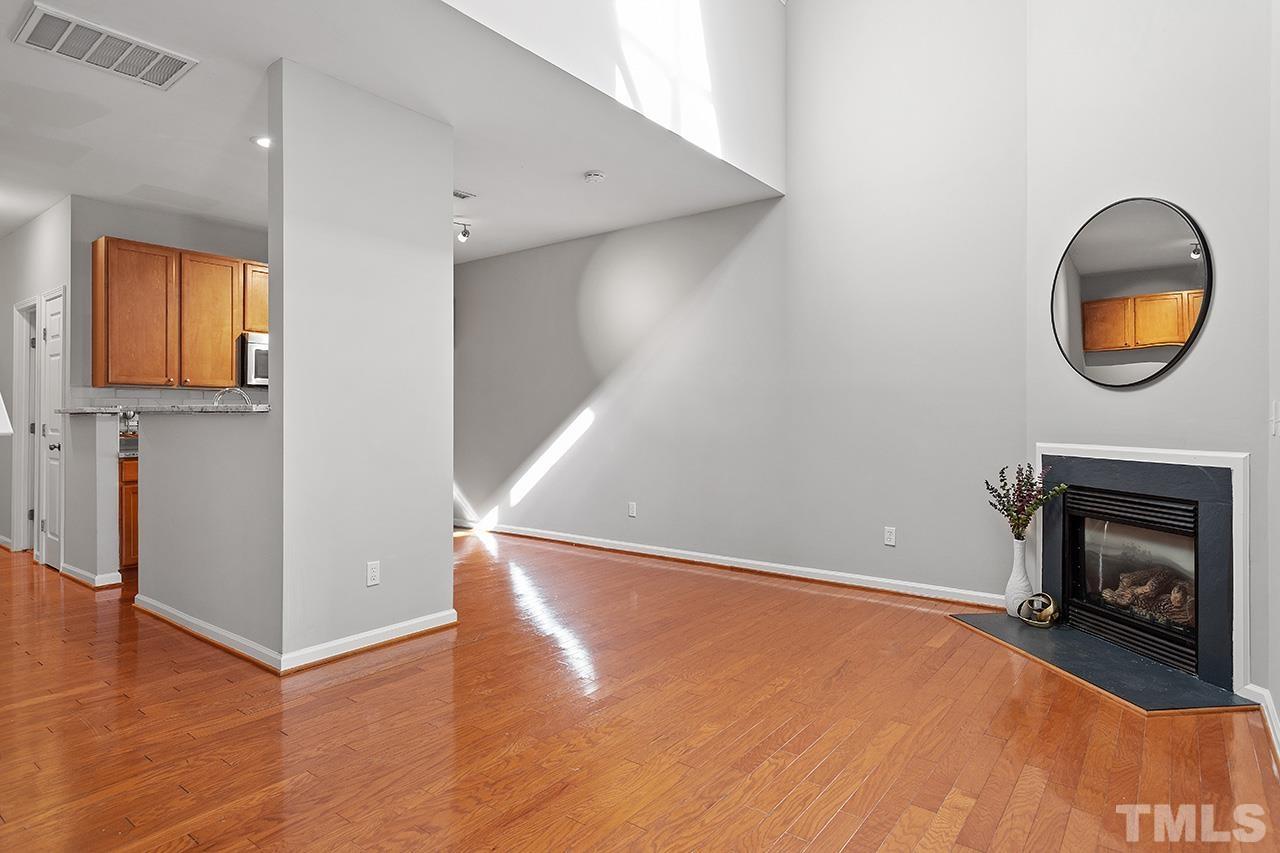 8516 Micollet Court Raleigh, NC 27613 - Photo 9 of 26 a view of an empty room with wooden floor and a fireplace