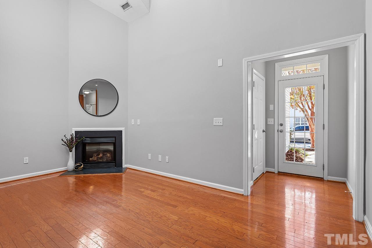 8516 Micollet Court Raleigh, NC 27613 - Photo 10 of 26 a view of an empty room with wooden floor fireplace and a window