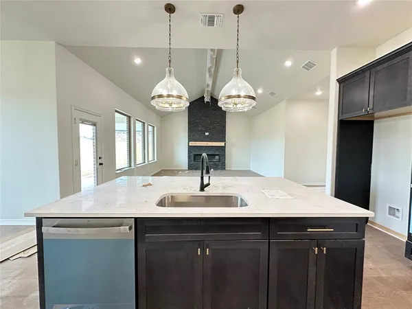 a kitchen with a sink a chandelier and wooden floor