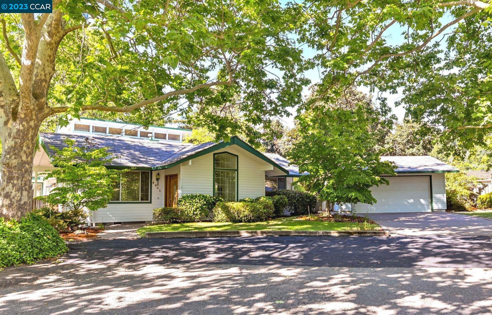 a view of a house with a yard and large tree
