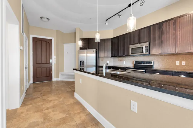 a kitchen with stainless steel appliances granite countertop a refrigerator a stove top oven a sink and dishwasher