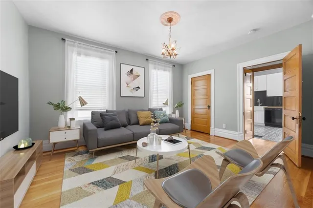 a living room with furniture a chandelier and a flat screen tv