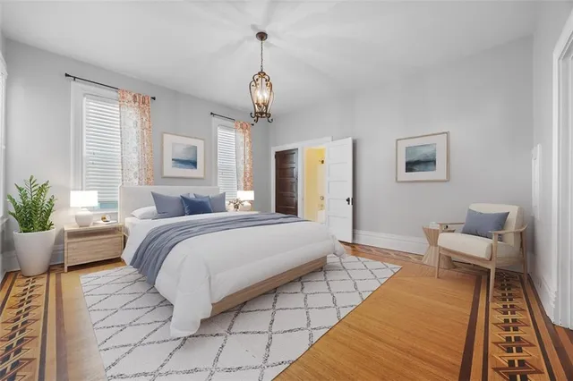 a spacious bedroom with a bed a couch and potted plant with the wooden floor