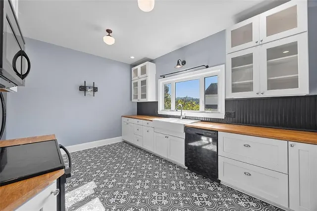 a large white kitchen with a sink a stove a microwave and cabinets