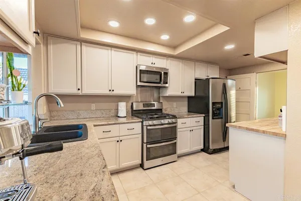 a kitchen with stainless steel appliances granite countertop a stove top oven a sink dishwasher a refrigerator and a cabinets with wooden floor