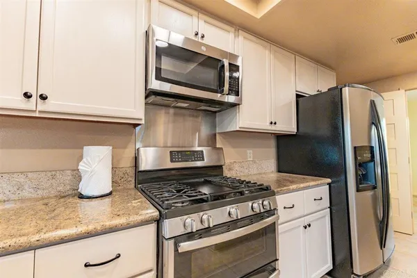 a kitchen with stainless steel appliances granite countertop a refrigerator stove and microwave