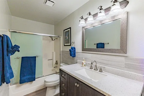 a bathroom with a granite countertop sink a toilet and a mirror