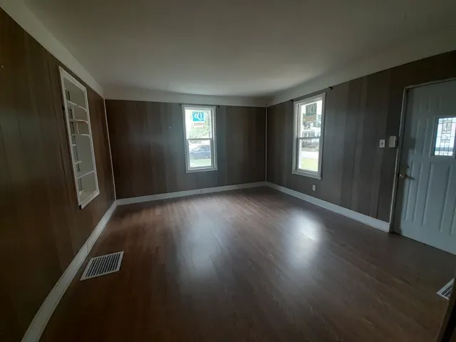 an empty room with wooden floor and windows
