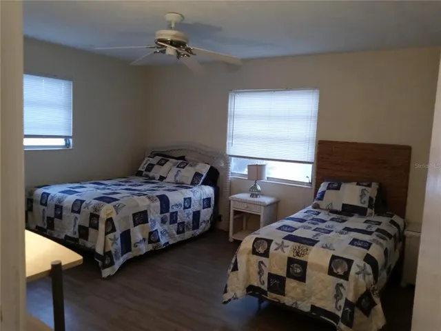 a bedroom with a bed a dresser with wooden floor
