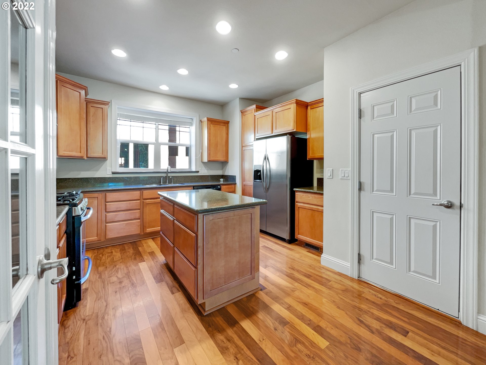12111 Southeast High Creek Road Happy Valley, OR 97086 - Photo 5 of 14 a kitchen with stainless steel appliances granite countertop a refrigerator a sink dishwasher and wooden cabinets with wooden floor