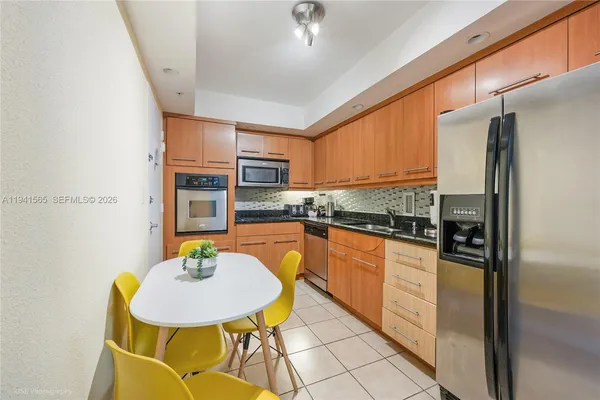 a kitchen with stainless steel appliances granite countertop a sink a stove a dining table and chairs