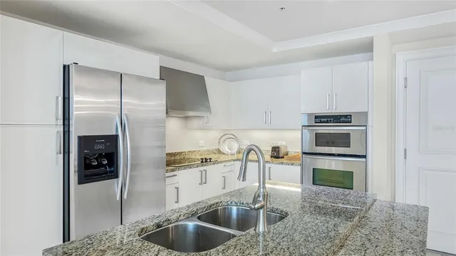 a kitchen with stainless steel appliances granite countertop a sink and a refrigerator
