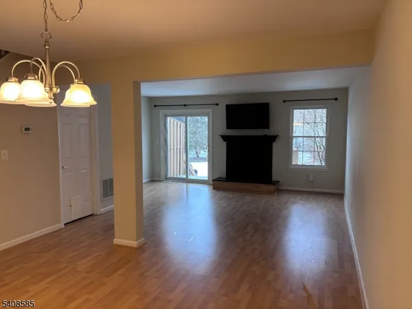 a view of a livingroom with wooden floor staircase and a kitchen