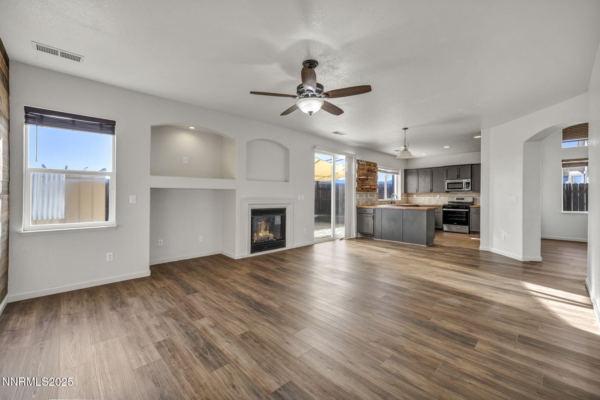 119 Red Oak Court Fernley, NV 89408 - Photo 9 of 64 a view of a livingroom with a fireplace a ceiling fan and wooden floor
