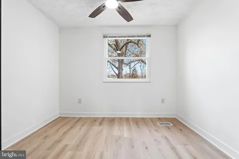 an empty room with a window and wooden floor