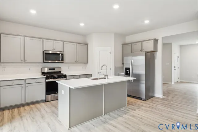 a kitchen with stainless steel appliances granite countertop a stove top oven a sink and a refrigerator