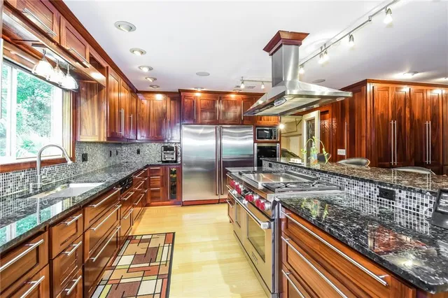 a kitchen with stainless steel appliances granite countertop a sink a stove and a wooden floors