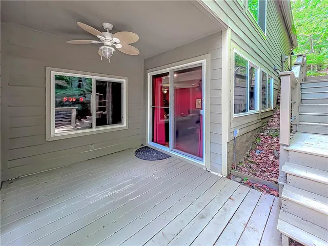 an empty room with wooden floor chandelier fan and windows