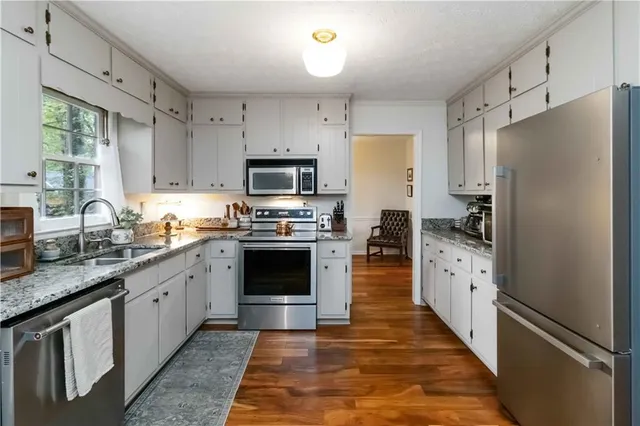 a large kitchen with stainless steel appliances granite countertop a refrigerator stove microwave and sink