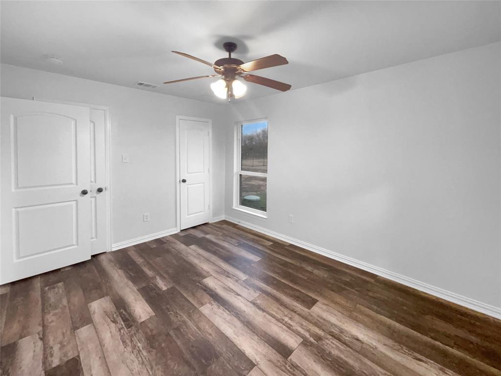 3915 Tower Circle Nevada, TX 75173 - Photo 20 of 29 a view of an empty room with wooden floor and a ceiling fan