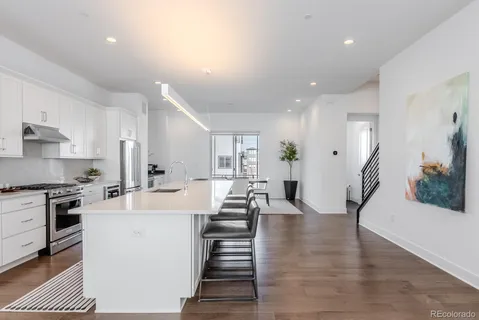 a large white kitchen with lots of counter space a sink appliances and cabinets