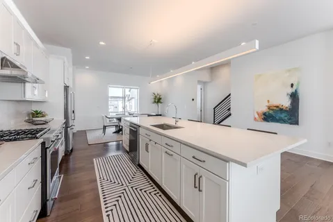 a large white kitchen with stainless steel appliances a stove a sink dishwasher and cabinets