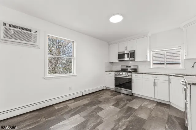 a kitchen with granite countertop white cabinets and stainless steel appliances