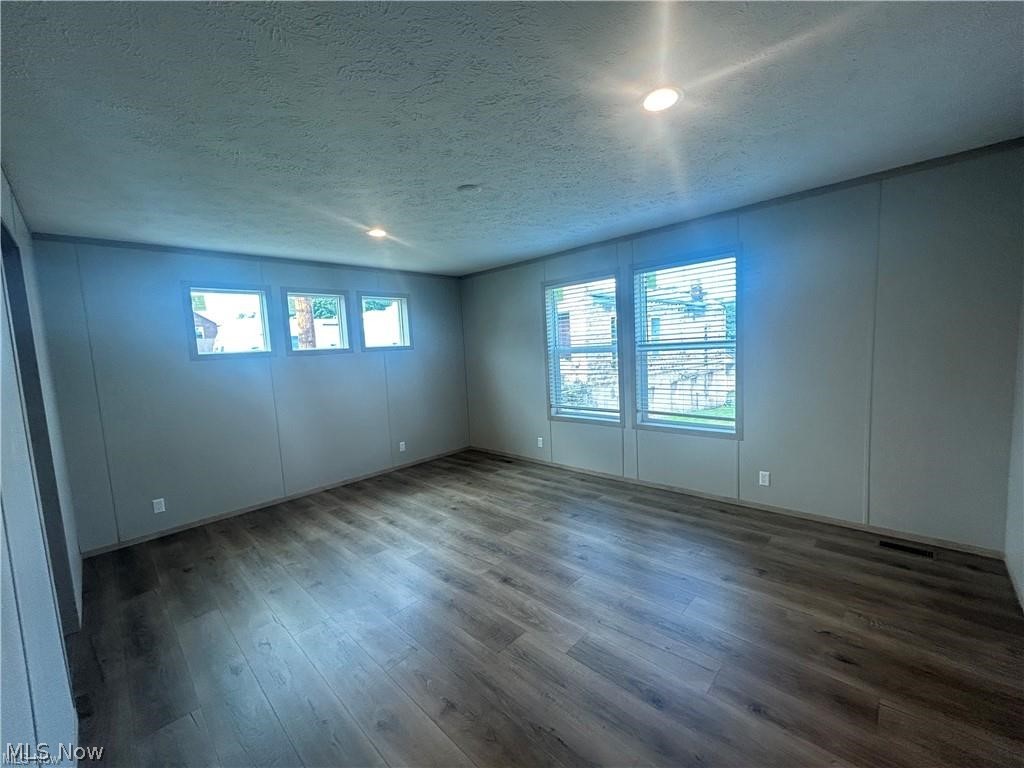252 Front Street Philo, OH 43771 - Photo 8 of 17 Empty room featuring a textured ceiling, dark wood-type flooring, a decorative wall, and recessed lighting