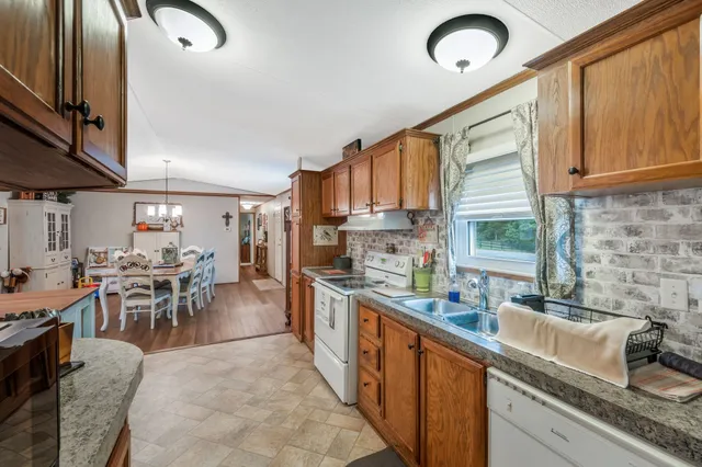 a kitchen with stainless steel appliances granite countertop sink stove refrigerator dining table and chairs