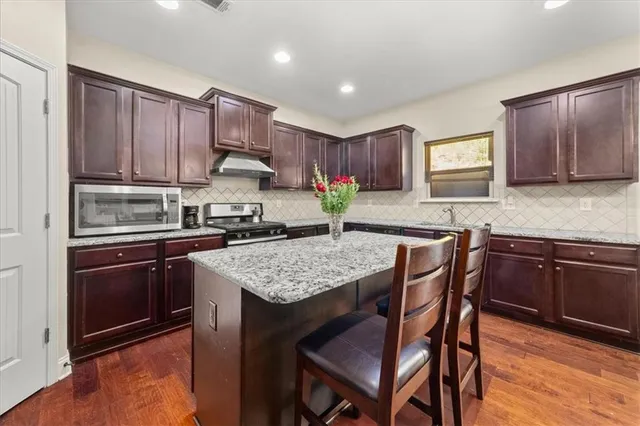 a kitchen with granite countertop wooden cabinets and a stove top oven