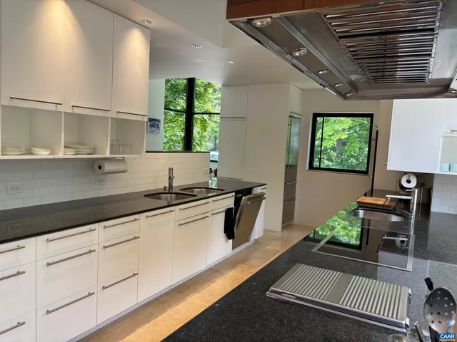 a kitchen with stainless steel appliances a sink a stove and white cabinets
