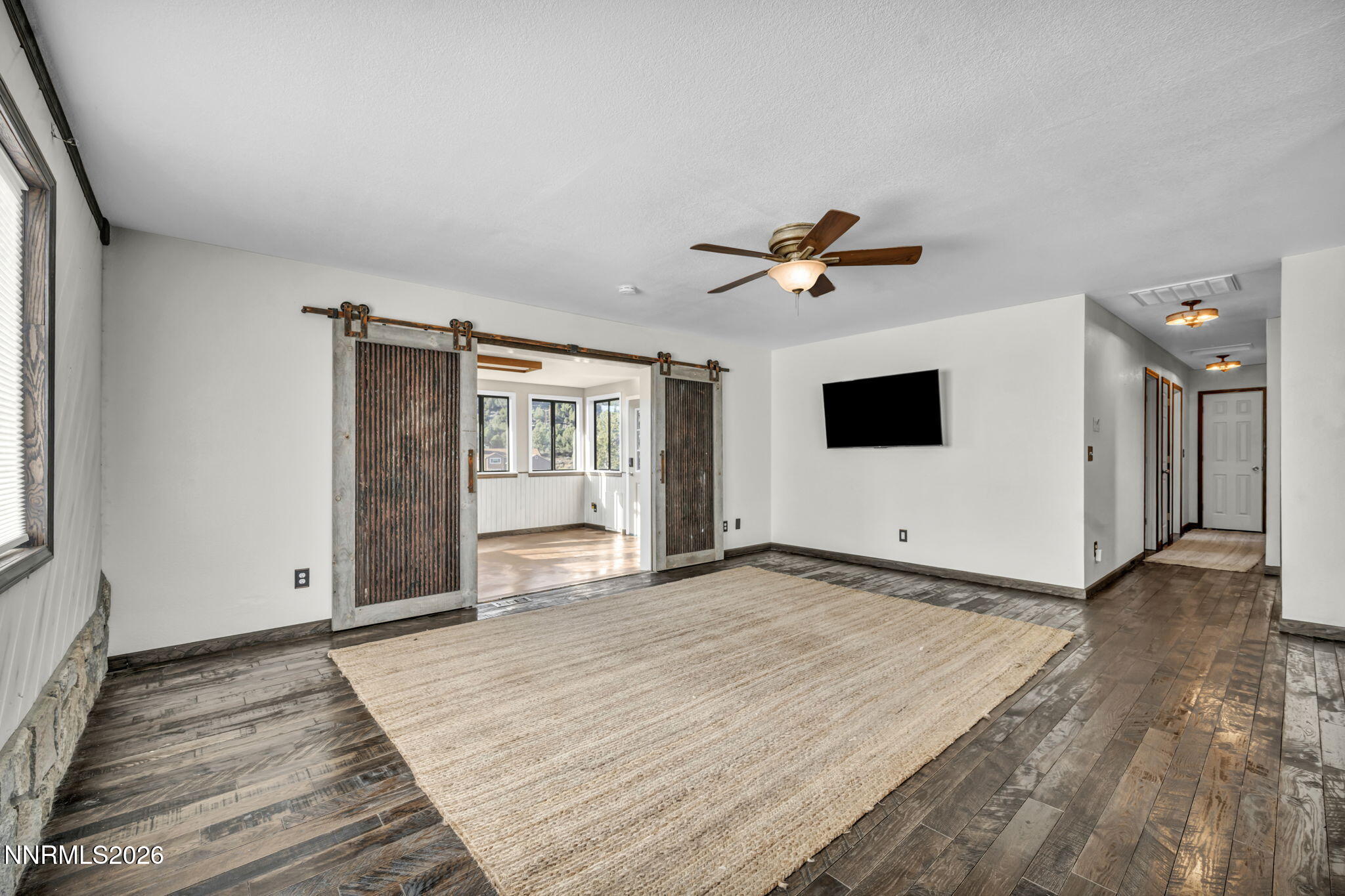 1835 Lousetown Road Reno, NV 89521 - Photo 22 of 60 a view of a livingroom with a flat screen tv wooden floor and a ceiling fan