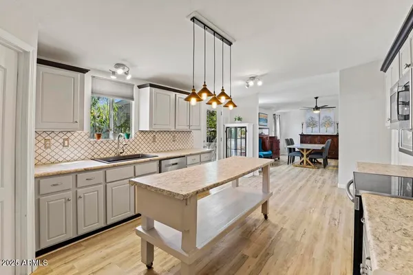 a large white kitchen with a stove a sink dishwasher and a fireplace with wooden floor