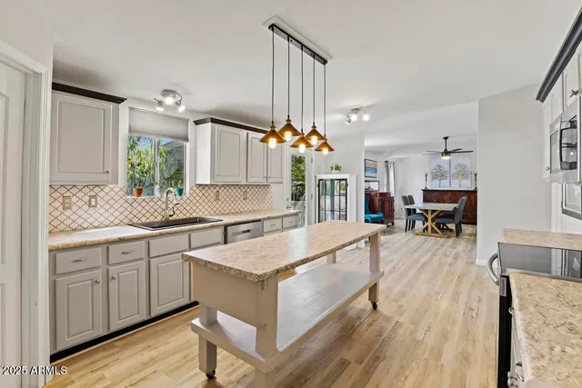 a large white kitchen with a stove a sink dishwasher and a fireplace with wooden floor